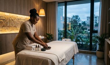 A therapist preparing a massage table with white towels and oils in a spa.